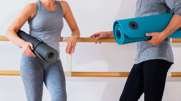 Senior fit man and woman holding yoga mats