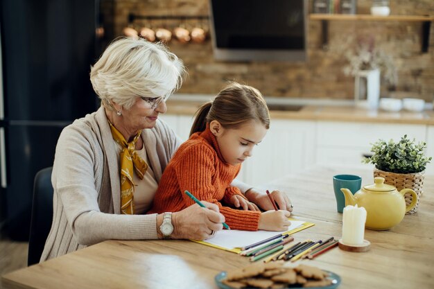 Senior grandmother coloring with her granddaughter at home