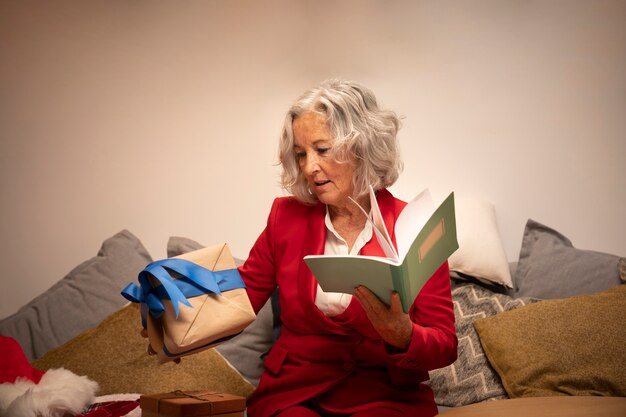 Старшая счастливая женщина держа книгу и подарок