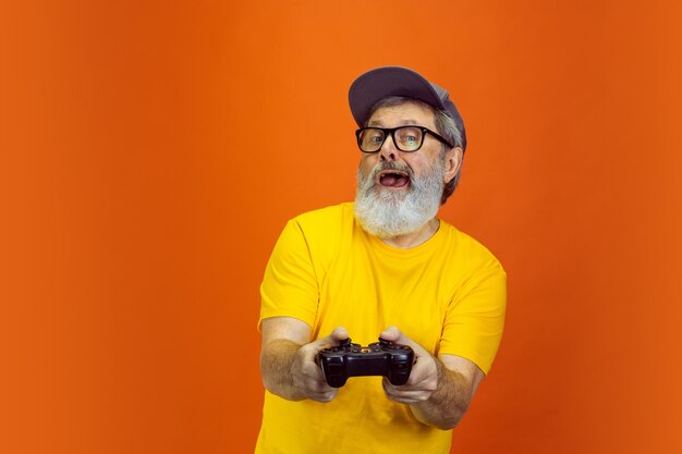 Senior hipster man using devices, gadgets on orange