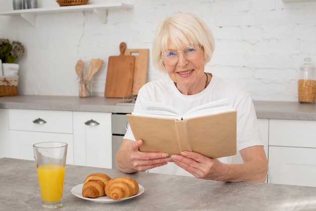 Free photo senior holding a book in the kitchen