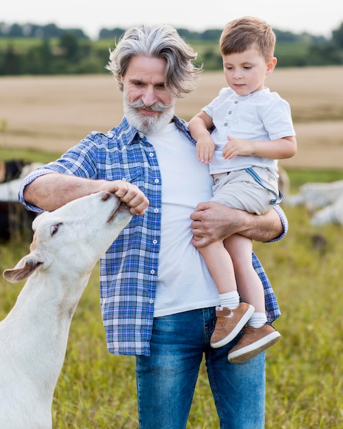 Foto gratuita senior holding ragazzino all'azienda agricola