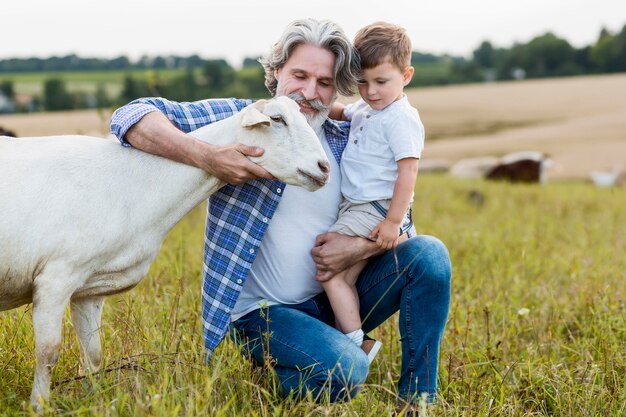 Senior holding little boy and hugging goats