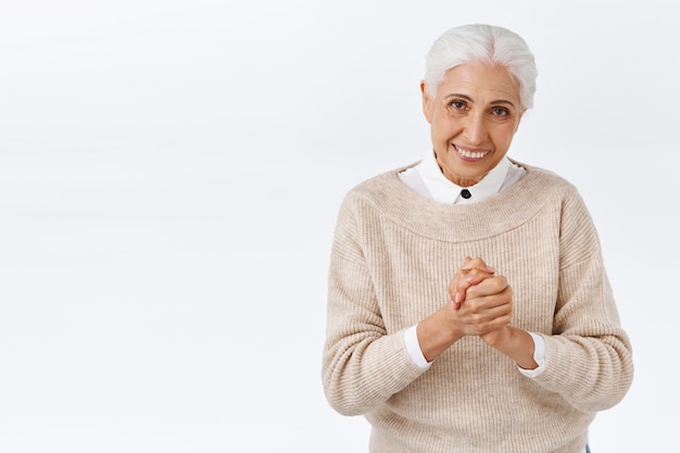 Free photo senior lady office worker thanking dearly for coming, bowing politely, press hands together grateful for invitation, smiling pleased, have signed good deal, standing white wall satisfied