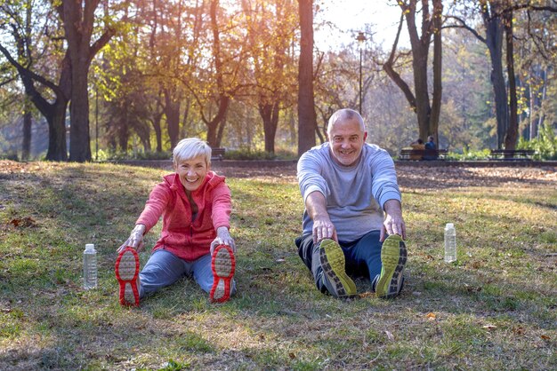 Senior male and female exercising in the park in autumn