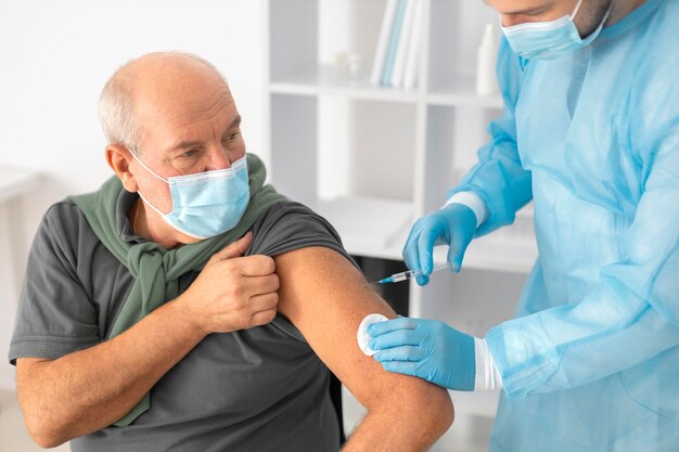 コロナウイルスの予防接種を受けている年配の男性患者