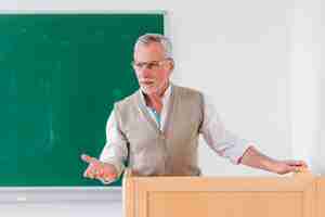 Free photo senior male professor explaining lesson near chalkboard