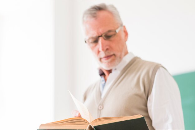 Senior male professor in glasses reading book