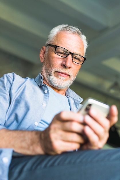 Senior male wearing black glasses using cellphone