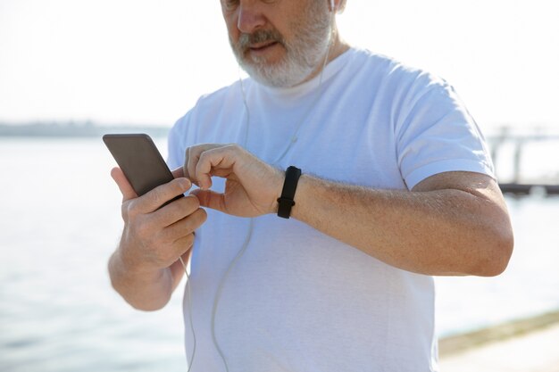 Senior man as runner with fitness tracker at the riverside.