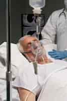 Бесплатное фото Старший мужчина дышит с помощью специального оборудования в больнице