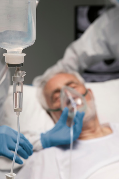 Старший мужчина дышит с помощью специального оборудования в больнице