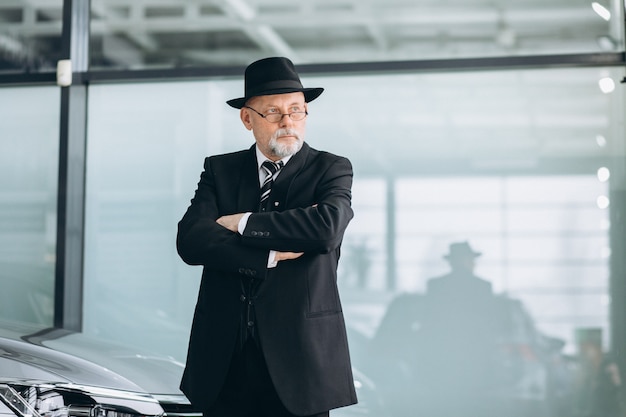 Senior man in a car showroom choosing a car