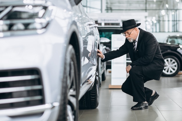 Senior man in a car showroom choosing a car