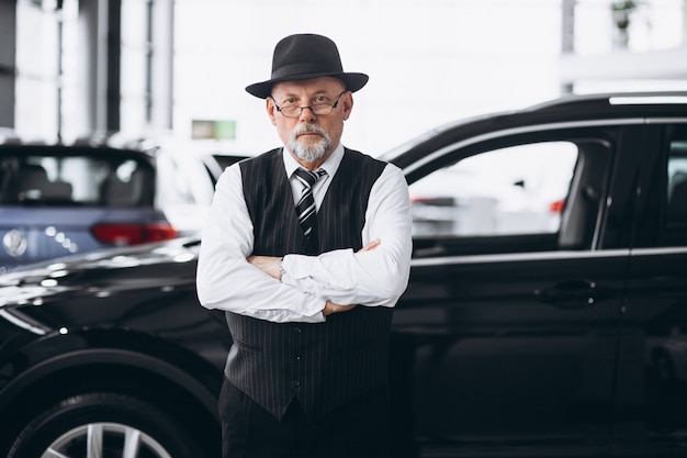 Foto gratuita uomo senior in una sala d'esposizione dell'automobile che sceglie un'automobile