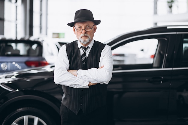 Старший мужчина в автосалоне, выбирая автомобиль