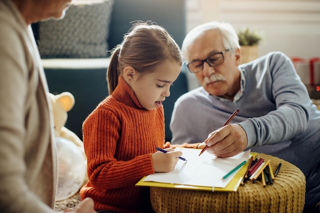 Foto gratuita uomo anziano che colora con sua nipote a casa