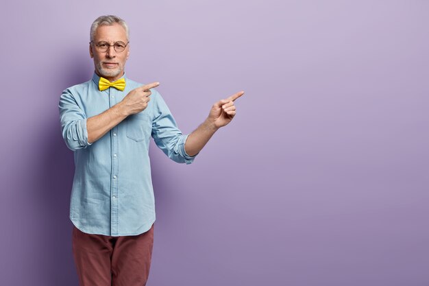 Senior man in denim shirt and yellow bowtie