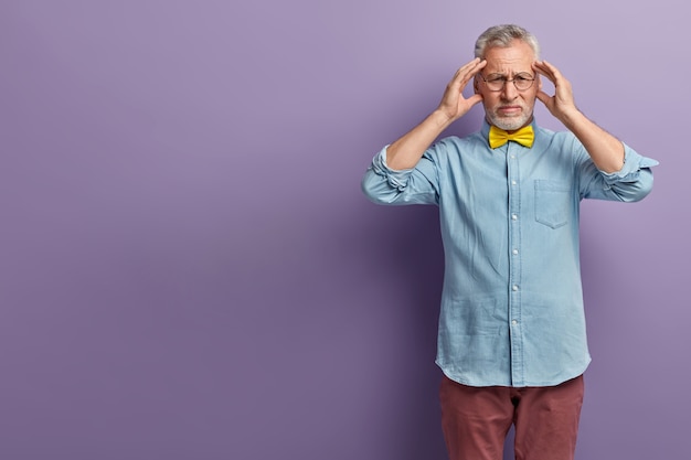 Senior man in denim shirt and yellow bowtie