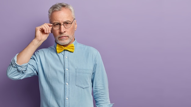 Free photo senior man in denim shirt and yellow bowtie