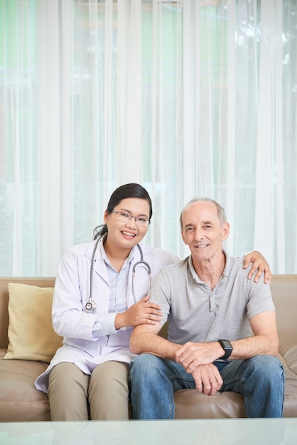 Senior man and doctor sitting on sofa in the living room