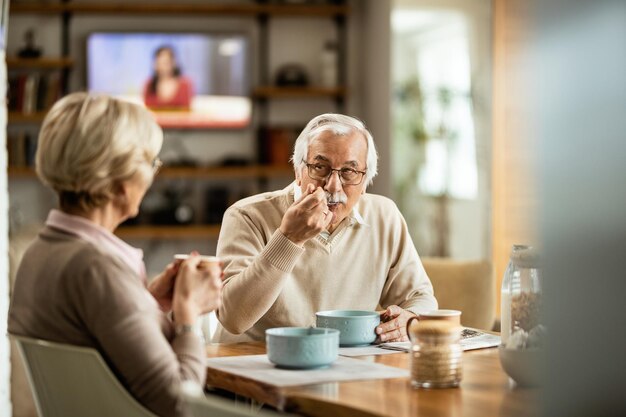 Senior man eating breakfast with his wife in the morning at dining table