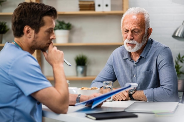 Старший мужчина беспокоится, анализируя свои медицинские отчеты с врачом во время приема у врача