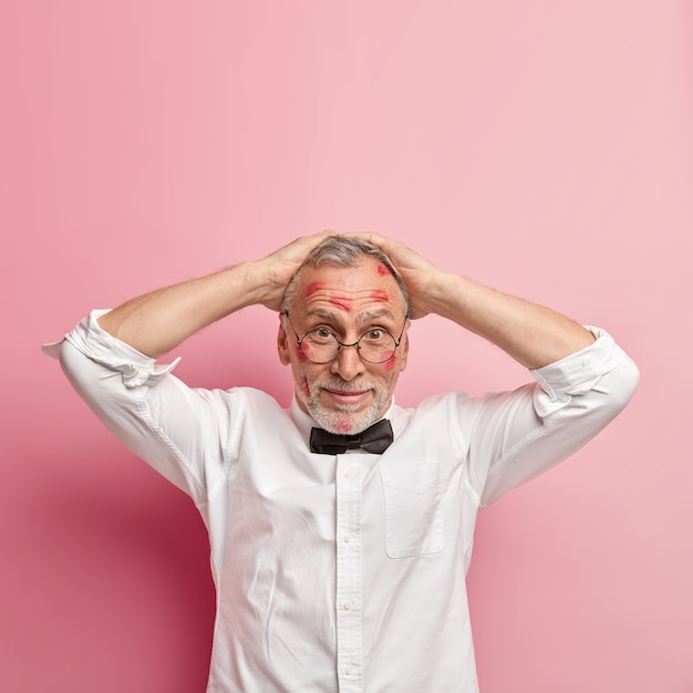 Free photo senior man having lipstick stains on face