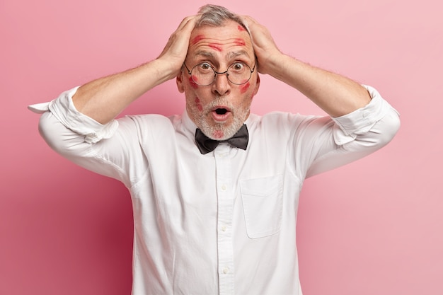 Free photo senior man having lipstick stains on face