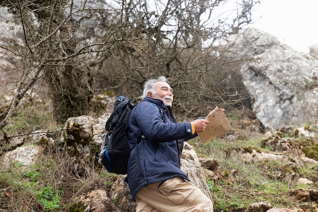 Foto gratuita uomo anziano che fa un'escursione con il colpo medio della mappa