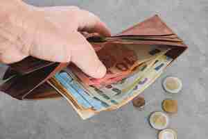 Free photo senior man holds a wallet with euro banknotes in his hand euro banknotes in the wallet wallet with money in a man's hand background idea of paying taxes buying or paying for services