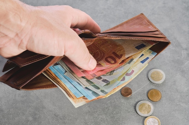 Senior man holds a wallet with euro banknotes in his hand euro banknotes in the wallet Wallet with money in a man's hand background idea of paying taxes buying or paying for services