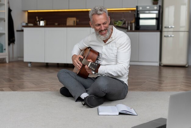 Senior man at home on the floor taking guitar lessons