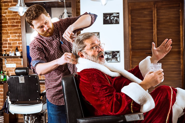 크리스마스 전에 이발소에서 그의 개인 마스터를 면도하는 산타 클로스 의상 수석 남자