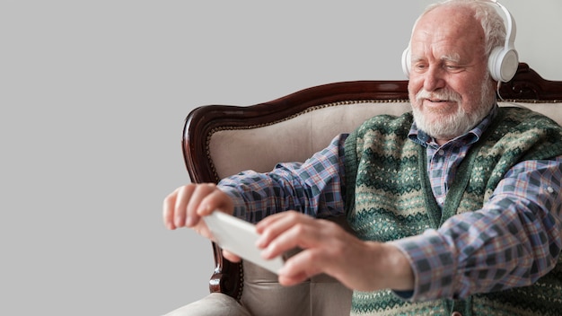 Free photo senior man listening music on mobile