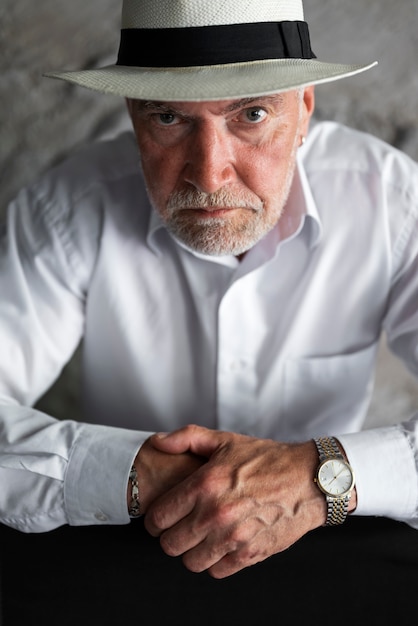 Senior man posing in white shirt and hat