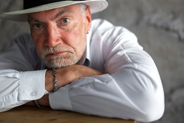 Senior man posing in white shirt and hat