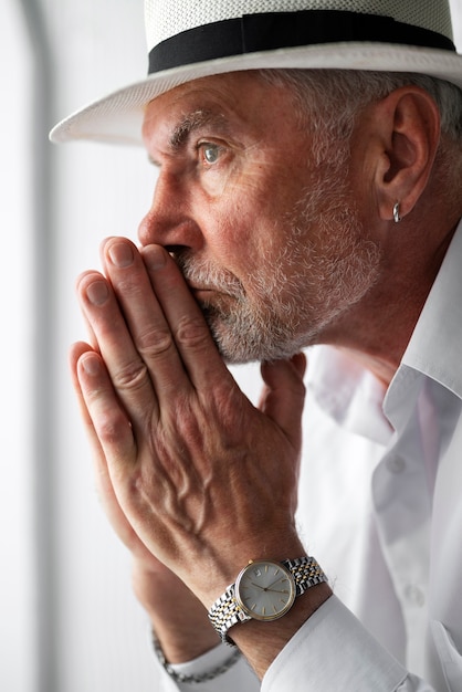 Senior man posing in white shirt and hat