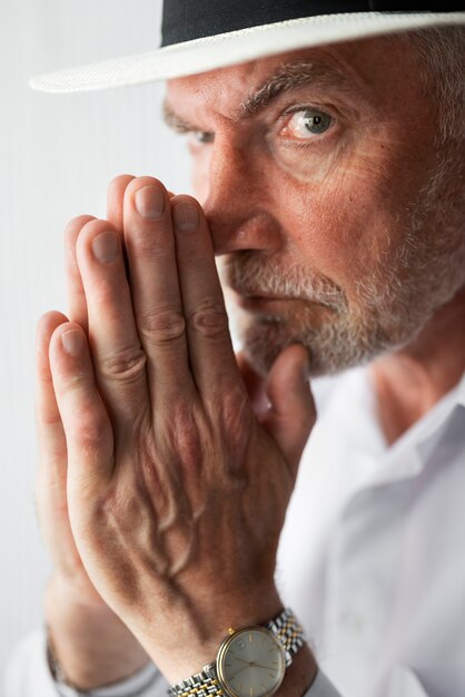 Senior man posing in white shirt and hat