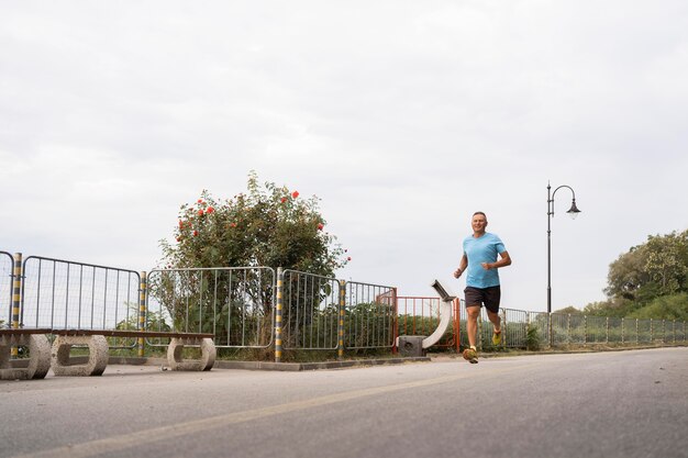 Senior man practicing jogging outdoors through park