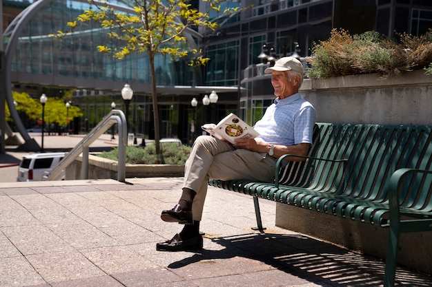 Старший мужчина читает книгу на скамейке на открытом воздухе