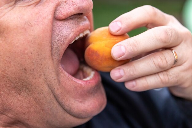 Free photo senior man ready to bite into a peach