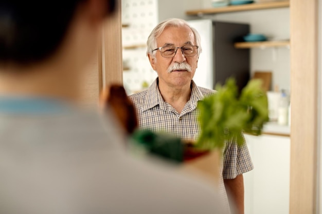 Senior man receiving groceries delivery from a courier at home