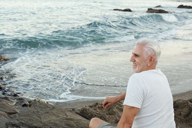 ビーチで休んで海を眺める年配の男性