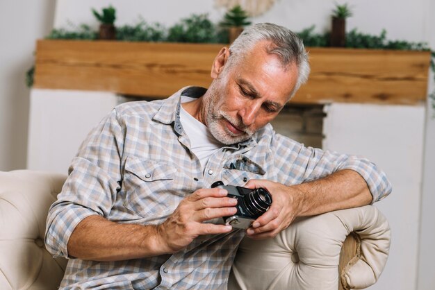 Senior man sitting on sofa looking the camera