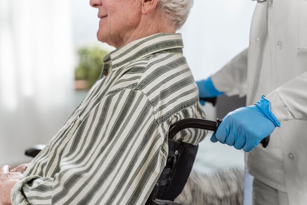 Senior man sitting in wheelchair next to a doctor