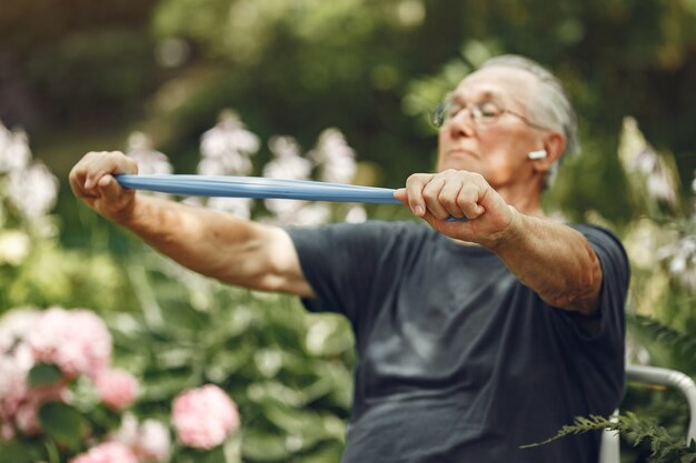 Senior man at summer park. Grangfather using a eraiser.