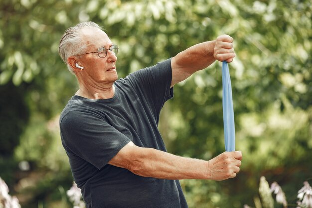 Senior man at summer park. Grangfather using a eraiser.