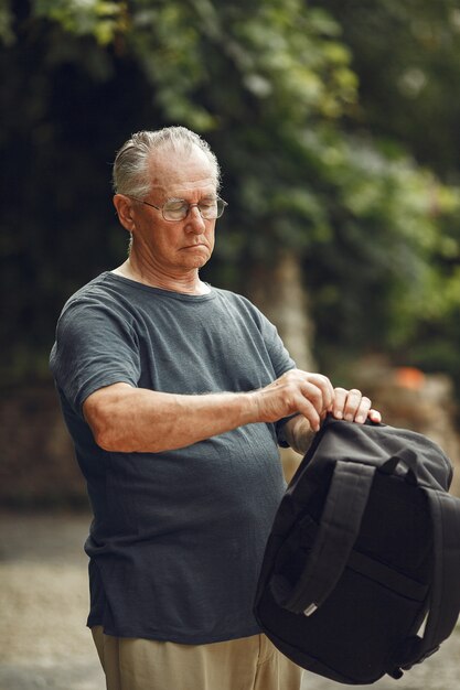 Senior man at summer park. Grangfather with a backpack.