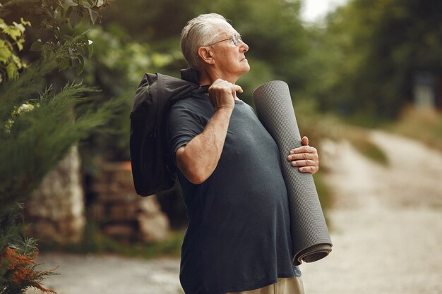 Senior man at summer park. Grangfather with a mat.